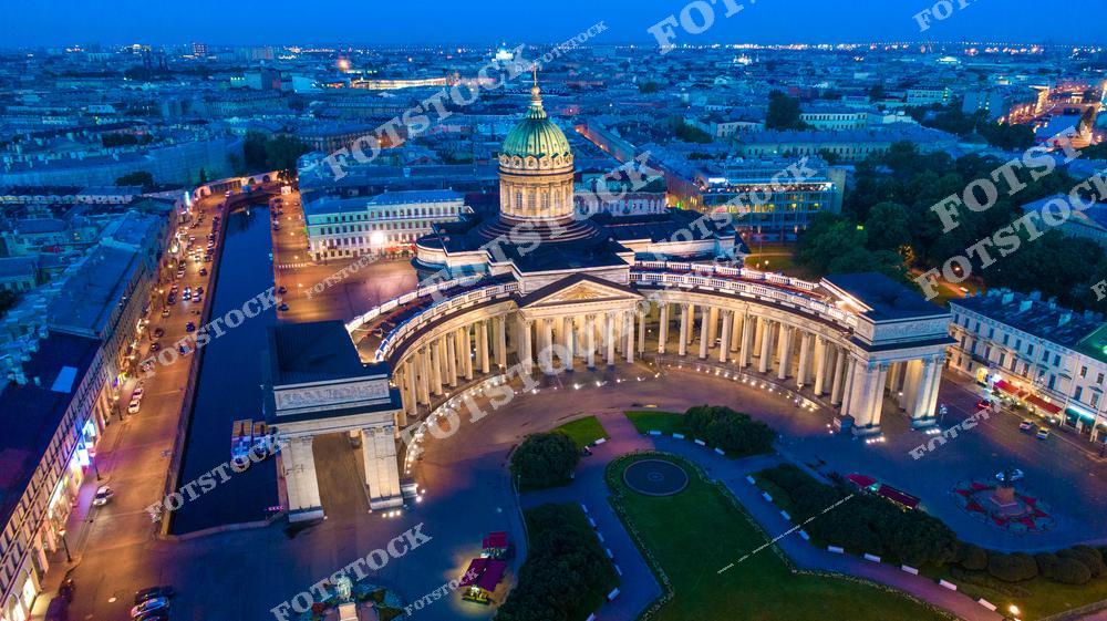 Панорамная фотография Казанского собора в Санкт-Петербурге с высоты птичьего полета в вечернее время. На снимке виден Невский проспект, исторические здания и архитектурные памятники города. Съемка с дрона позволяет оценить масштаб архитектурного ансамбля, панораму площади и вечерние огни Петербурга, создавая атмосферу величия и исторической значимости. Фотография идеально подходит для туристических публикаций, фотостоков, материалов о культуре и архитектуре, рекламы и оформления интерьеров. Вид с высоты раскрывает красоту и гармонию архитектуры Казанского собора и его окружения в историческом центре города.
